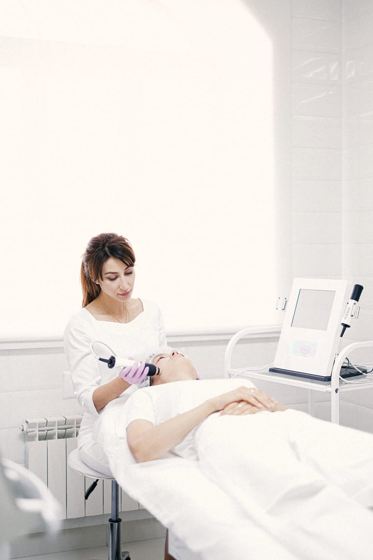 A clinician seated beside a client on a treatment bed in a bright, spacious clinic room