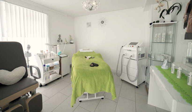 A treatment room with a laser system on a trolley beside a prepared bed