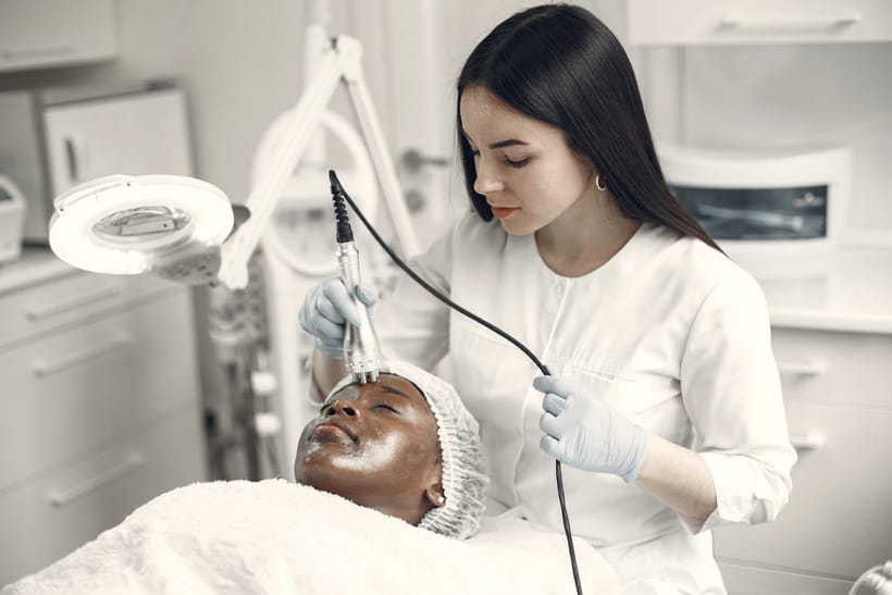 A clinician guides a handheld resurfacing device across a client's cheek